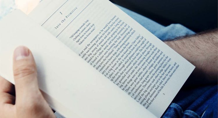 Person reading a book with detailed text on a page.